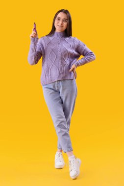 Young woman with disposable electronic cigarette on yellow background