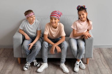 Happy little friends sitting on sofa near grey wall