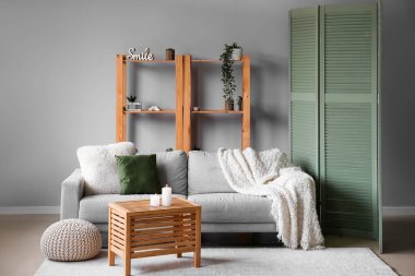 Interior of living room with sofa, shelving unit and folding screen