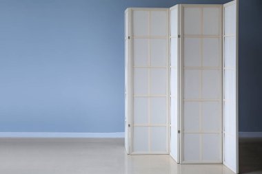 Beige folding screen near grey wall