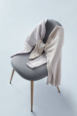 Chair with sweaters on grey background