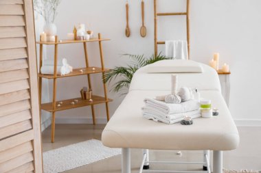 Spa composition with burning candles on couch in light salon