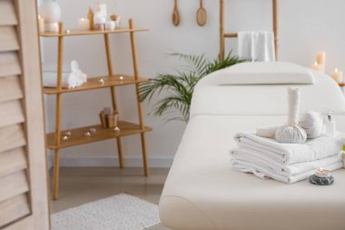 Spa composition with burning candles on couch in light salon