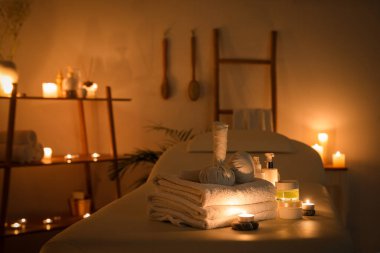Spa composition with burning candles on couch in dark salon