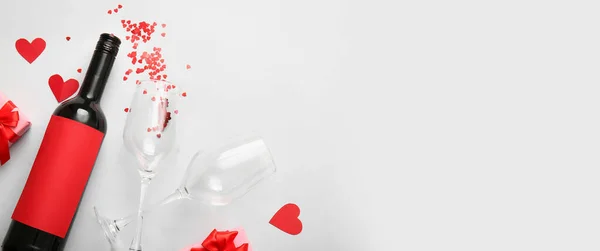Composition with bottle of wine, decor and glasses on light background with space for text. Valentines Day celebration