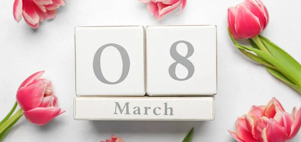 Calendar with date of International Women's Day and tulip flowers on white background