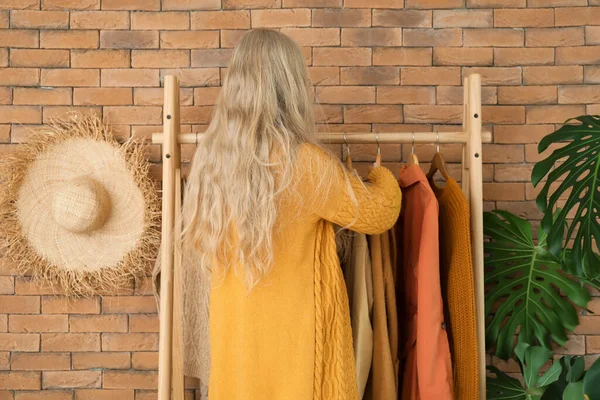 Blonde Woman Rack Warm Clothes Brick Wall — Stock Photo, Image