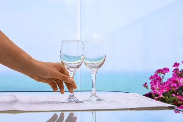Woman with wine glasses at table on balcony, closeup