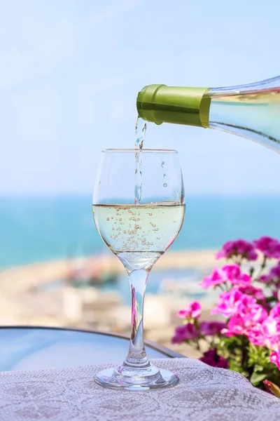 Pouring of wine from bottle into glass on balcony, closeup