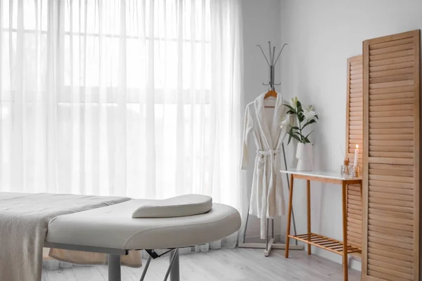 Interior of spa salon with couch, bathrobe and table