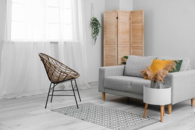 Interior of living room with sofa and wicker chair grass near window