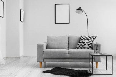 Interior of living room with grey sofa, coffee table and lamp near grey wall