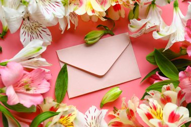Composition with beautiful alstroemeria flowers and envelope on pink background, closeup. Mother's day celebration
