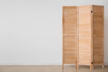 Wooden folding screen near white wall