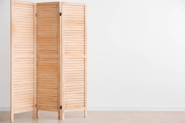 Wooden folding screen near white wall