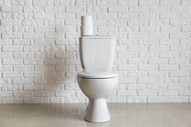 Modern toilet bowl near white brick wall