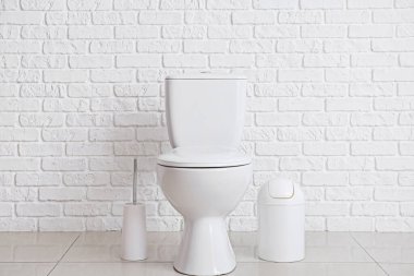 Modern toilet bowl near white brick wall