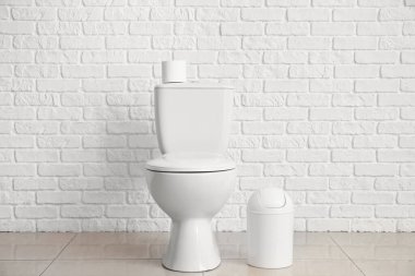 Modern toilet bowl near white brick wall