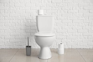 Modern toilet bowl near white brick wall