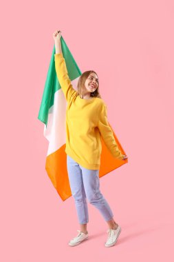 Young woman with flag of Ireland on pink background