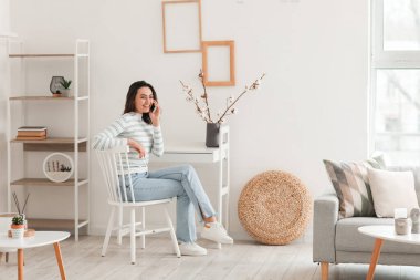 Young woman talking by smartphone at home