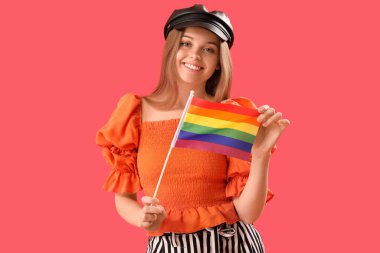 Beautiful young woman in hat with LGBT flag on red background