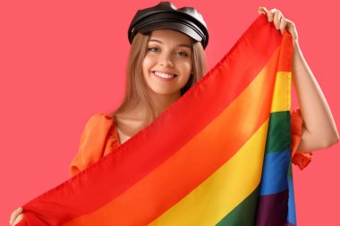 Beautiful young woman in hat with LGBT flag on red background