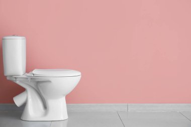 Ceramic toilet bowl near pink wall