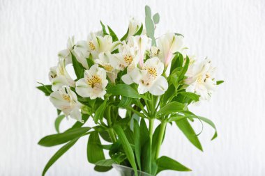 Bouquet of beautiful alstroemeria flowers near light wall, closeup