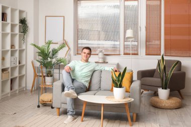 Young man resting on grey couch in living room