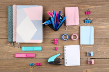 Holder with stationery and notebooks on wooden background