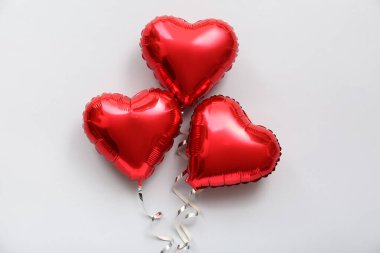 Red heart shaped balloons with ribbons on light background. Valentine's Day celebration