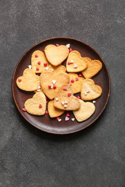 Plate of sweet heart shaped cookies on dark background. Valentines Day celebration