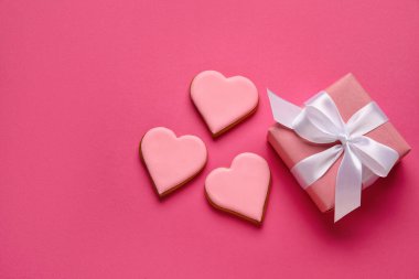 Beautiful gift box and heart shaped cookies on color background. Valentines Day celebration