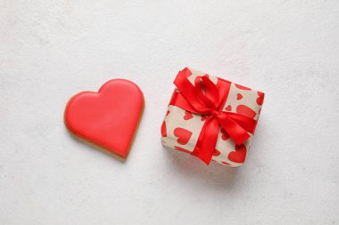 Tasty heart shaped cookie and gift box on light background. Valentines Day celebration