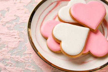 Plate with heart shaped cookies on pink grunge background, closeup. Valentines Day celebration