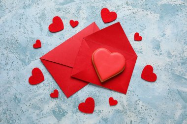 Red envelope and heart shaped cookie on blue grunge background. Valentines Day celebration