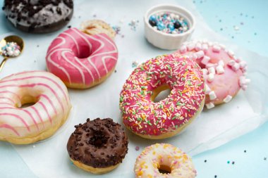 Parchment with different delicious donuts on blue background