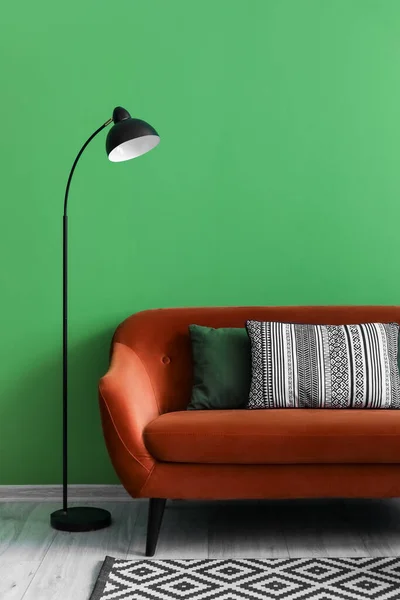 Brown sofa and lamp near green wall