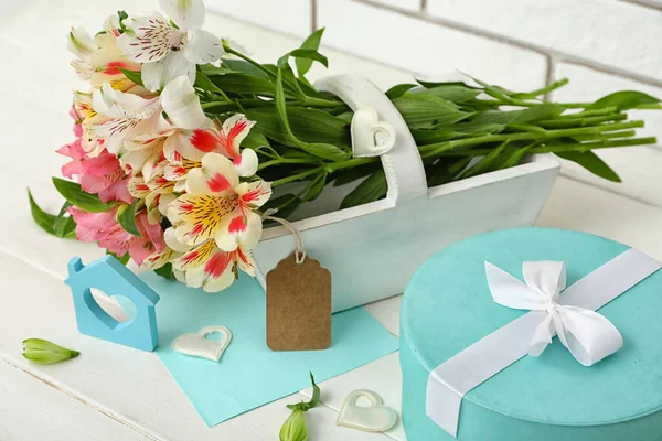 Beautiful alstroemeria flowers, gift box and decor on light wooden table, closeup. Mother\'s day celebration