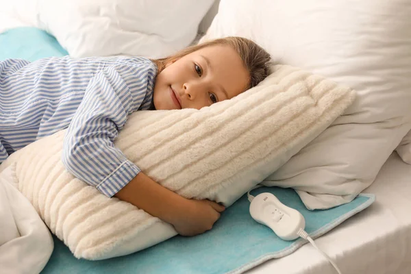 Little girl lying on electric heating pad in bedroom