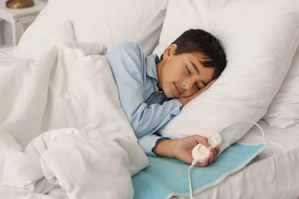 Little boy sleeping on electric heating pad in bedroom