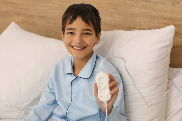 Little boy with electric heating pad in bedroom, closeup