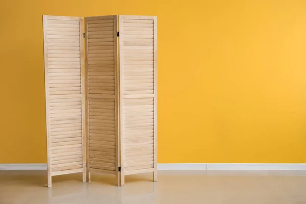 Wooden folding screen near yellow wall