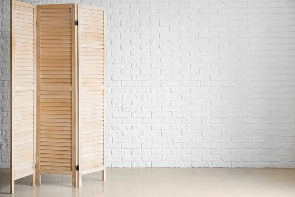 Wooden folding screen near white wall
