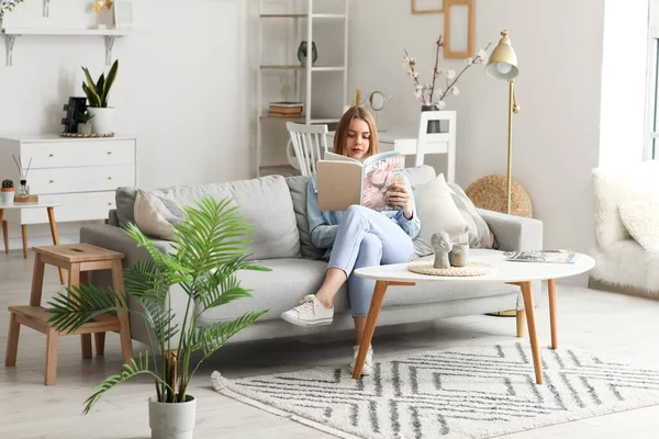 Young Woman Reading Magazine Grey Couch Home — Stock Photo, Image