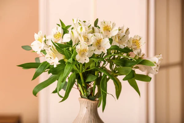 Vase with bouquet of alstroemeria flowers on beige background, closeup