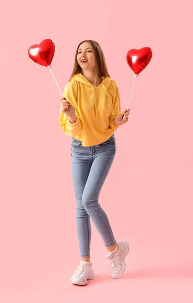 Young woman with heart-shaped balloons on pink background. Valentine\'s Day celebration