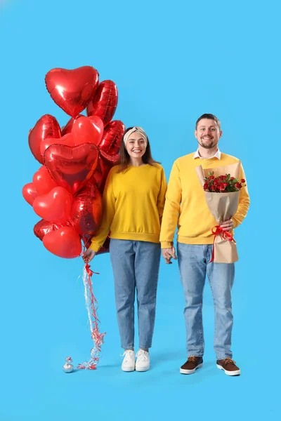 Happy couple in love with roses and balloons on blue background. Valentine's Day celebration