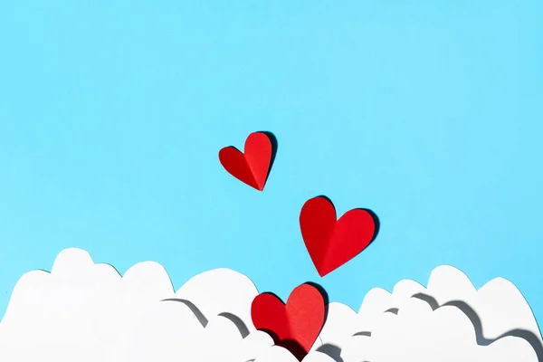 Composition with paper hearts and clouds on color background. Valentines Day celebration